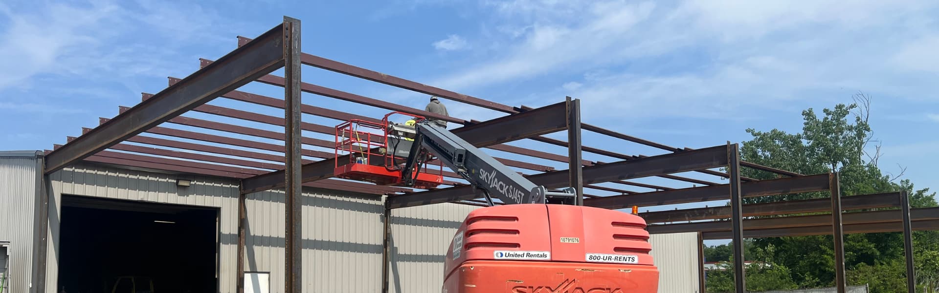 Steel frame installation in progress with workers welding from a lift.
