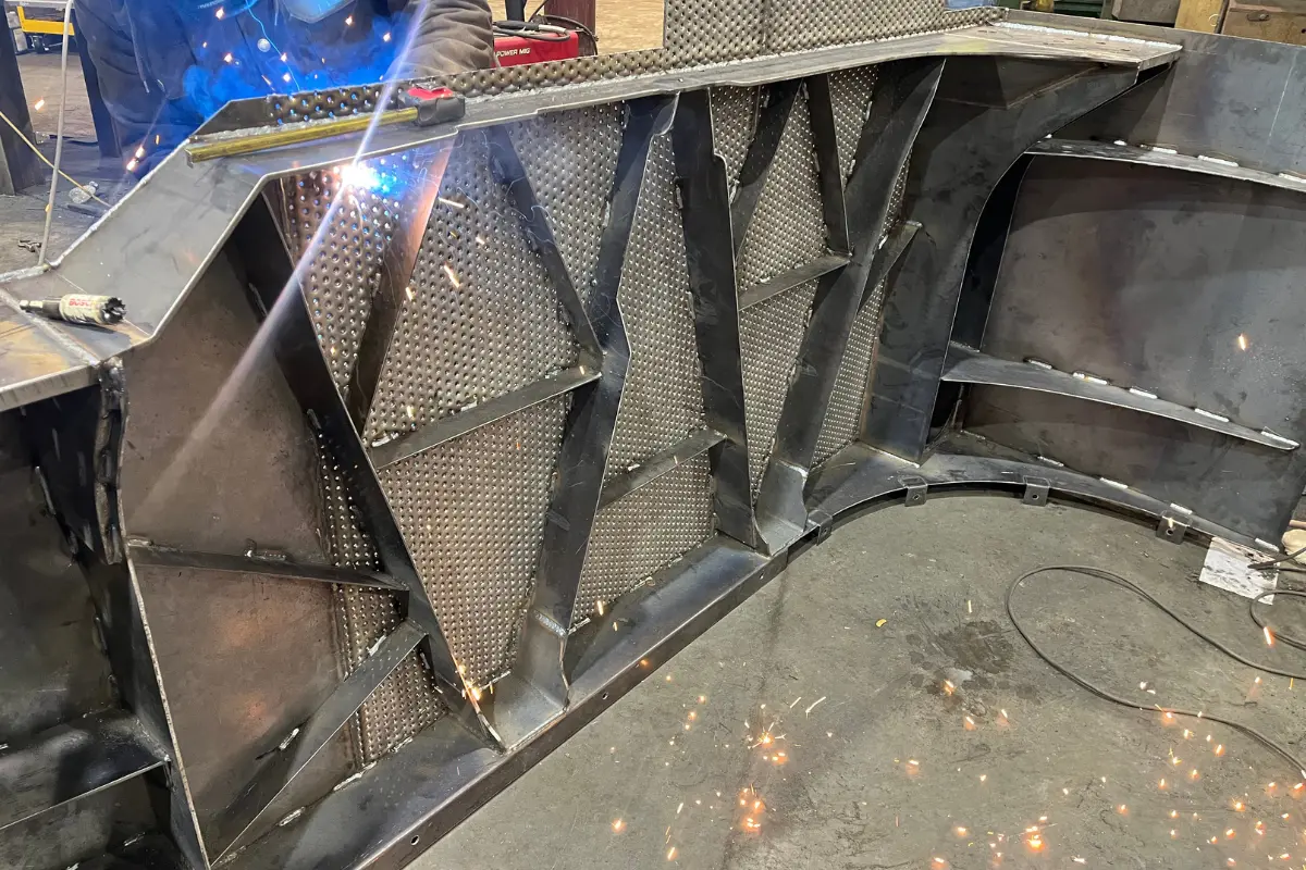 Welder working on diamond plate with sparks and blue welding arc.